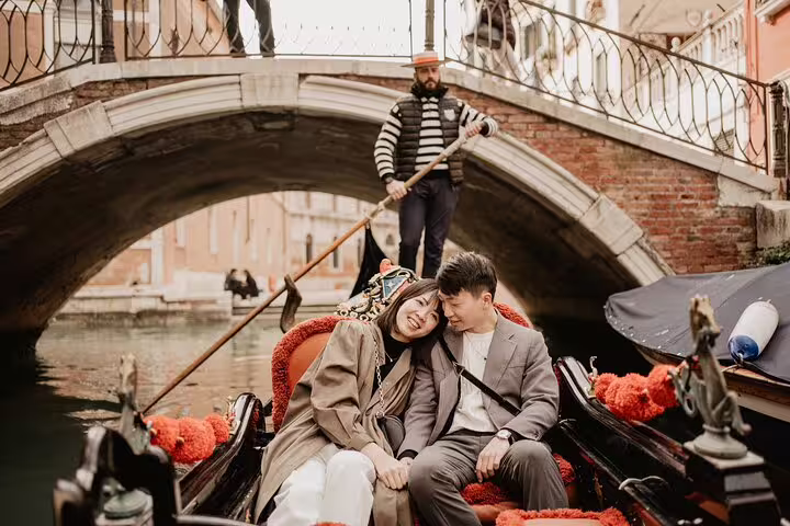 Couple cuddling on private Venice gondola under canal bridge, captured by professional photographer