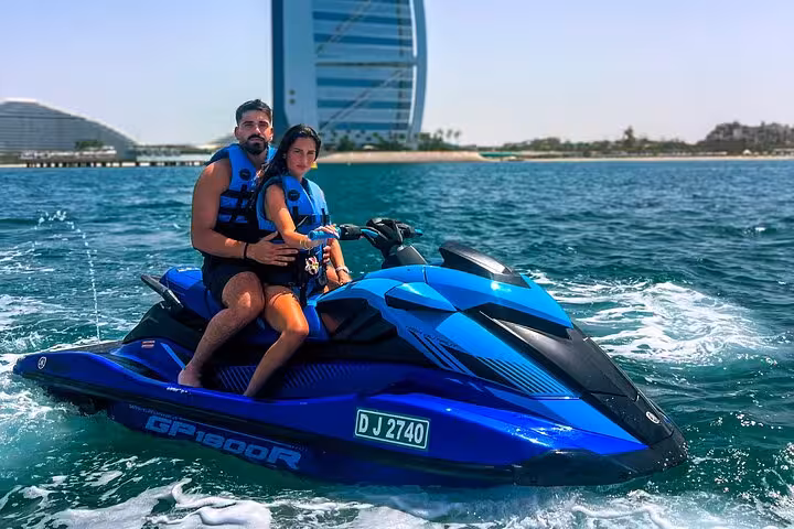 Couple enjoying a private jet ski ride near Dubai's Burj Al Arab with clear blue skies and vibrant water.