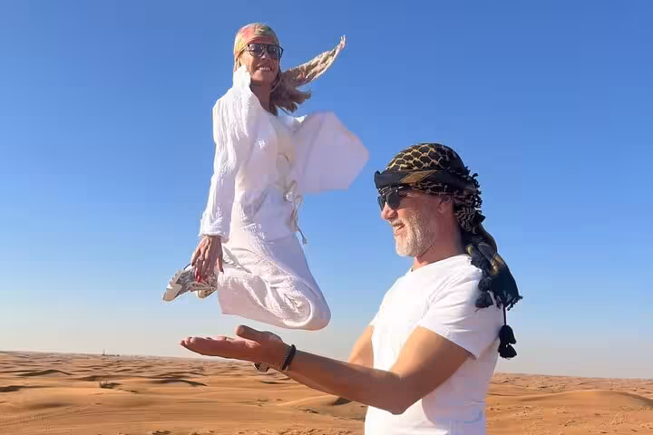 Couple enjoying dune photo stop on private morning desert safari, part of Abu Dhabi flamingos bird watching tour
