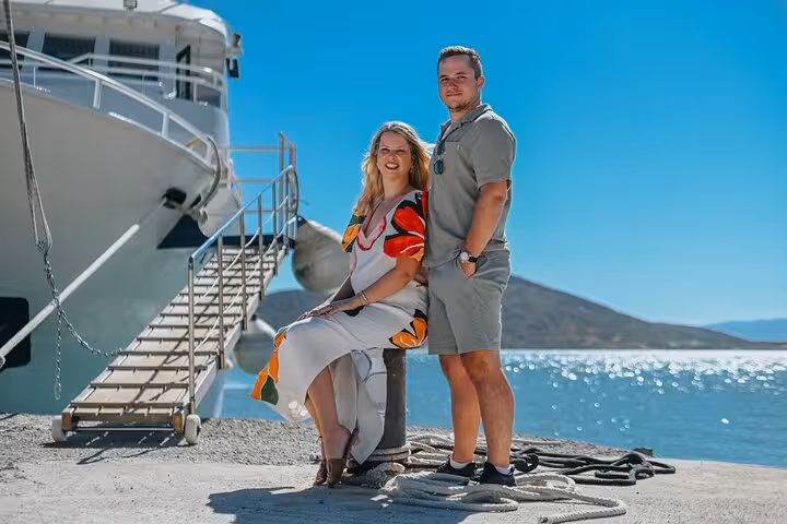 Couple enjoying a private photoshoot by a docked yacht in sunny Elounda, ideal for capturing holiday memories.