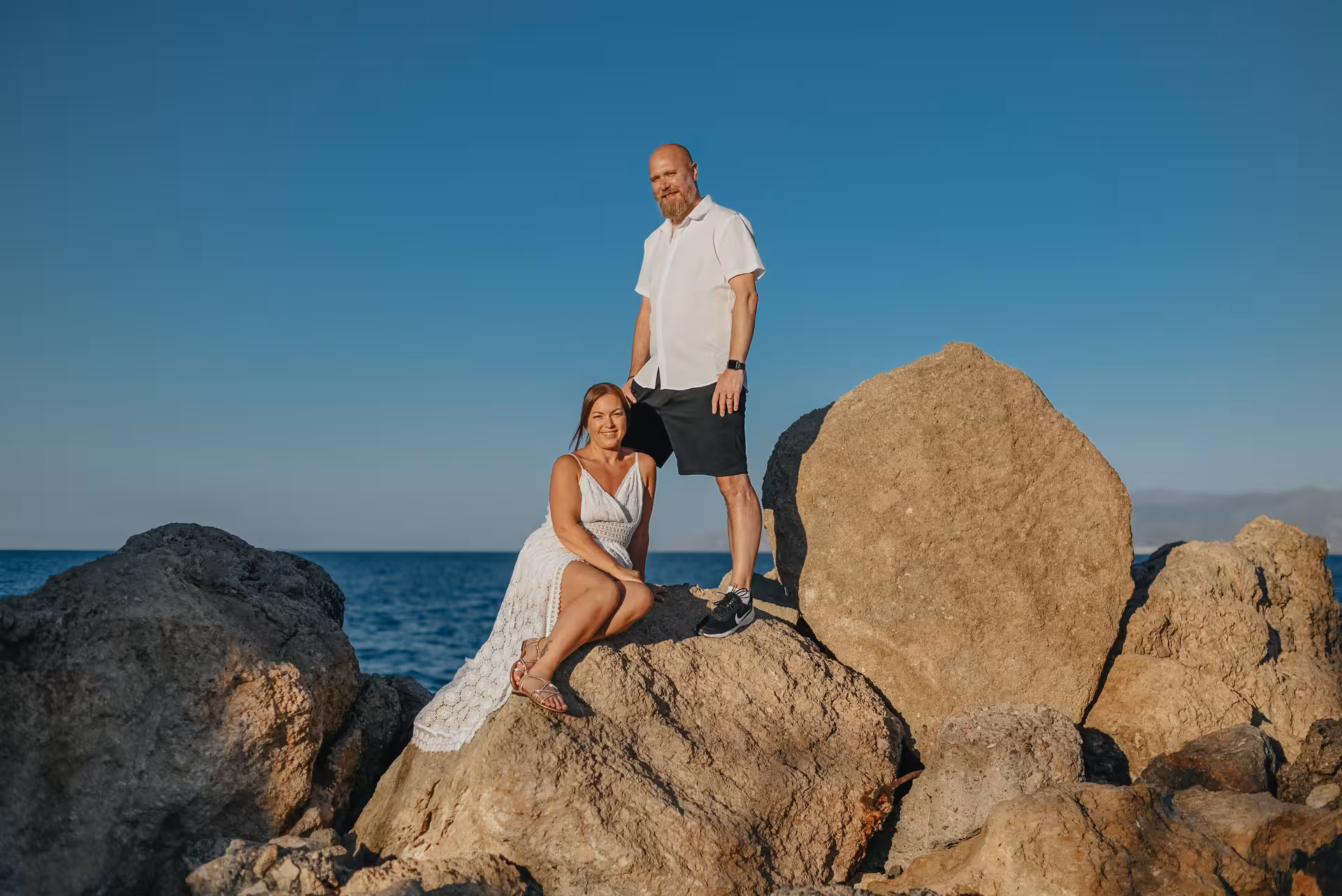 Couple posing on rocky coastline during a private photoshoot at The Port of Hersonissos.