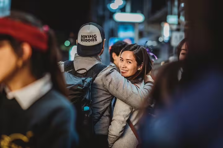 Couple enjoying an intimate moment in bustling Osaka nightlife during a private photoshoot tour.