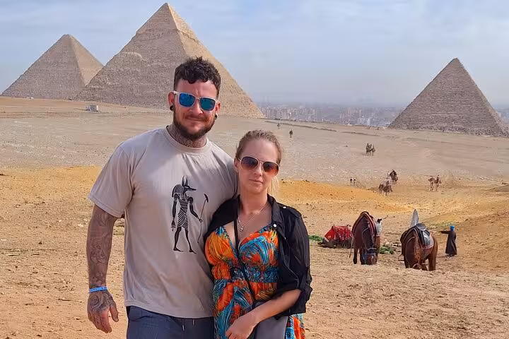 Couple enjoying a private tour with stunning views of the iconic Pyramids of Giza and camels in the background.