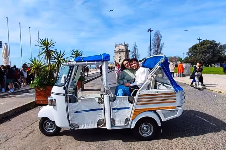Couple riding a private tuk tuk in Lisbon near Belém Tower on a 4-hour sightseeing tour