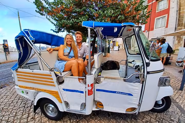 Couple riding a private tuk tuk in Lisbon on a 4-hour sightseeing tour through historic neighborhoods