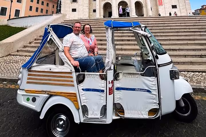 Couple on a 4-hour private Lisbon tuk tuk tour parked in front of the National Pantheon staircase