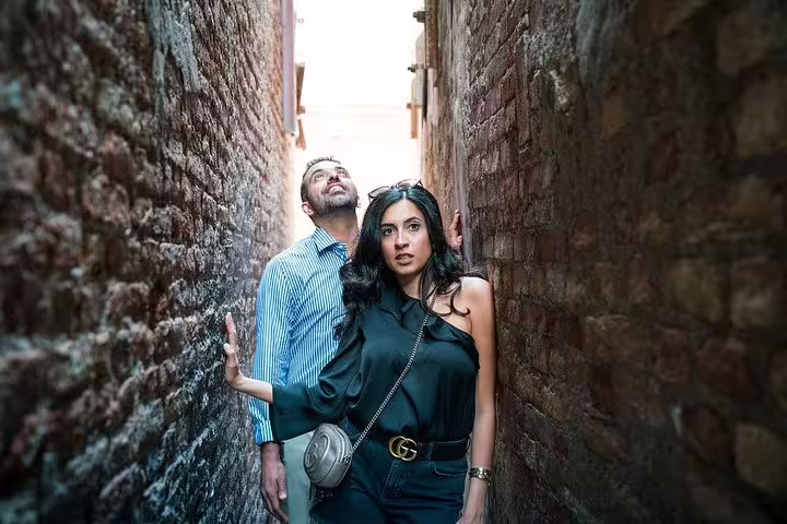 Couple exploring a narrow alleyway during a private photo shoot walking tour, surrounded by rustic brick walls.