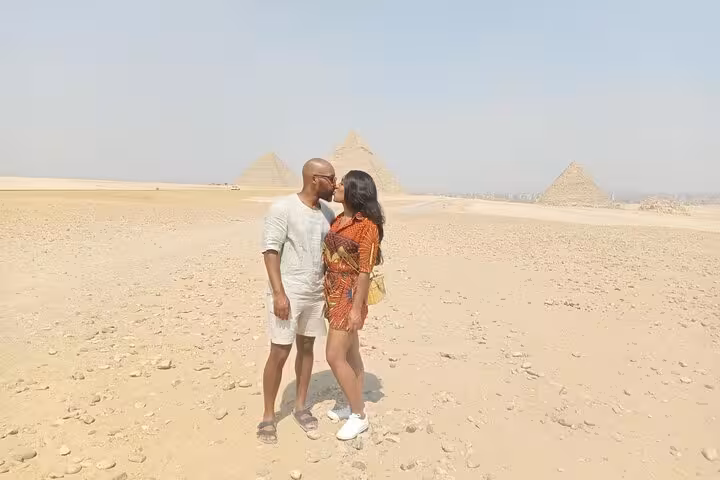 Couple posing by the Pyramids of Giza on a private Cairo tour with Saqqara visit and Egyptian lunch