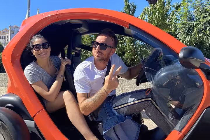Couple in red electric car on Sintra self-drive tour, exploring monuments like Pena Palace and Moorish Castle
