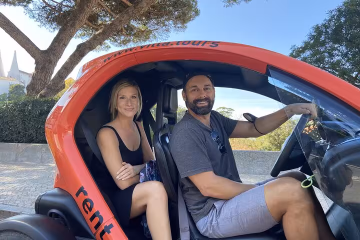Couple in a red rental car starting a self-drive tour in Sintra, Portugal, for monuments and coast views