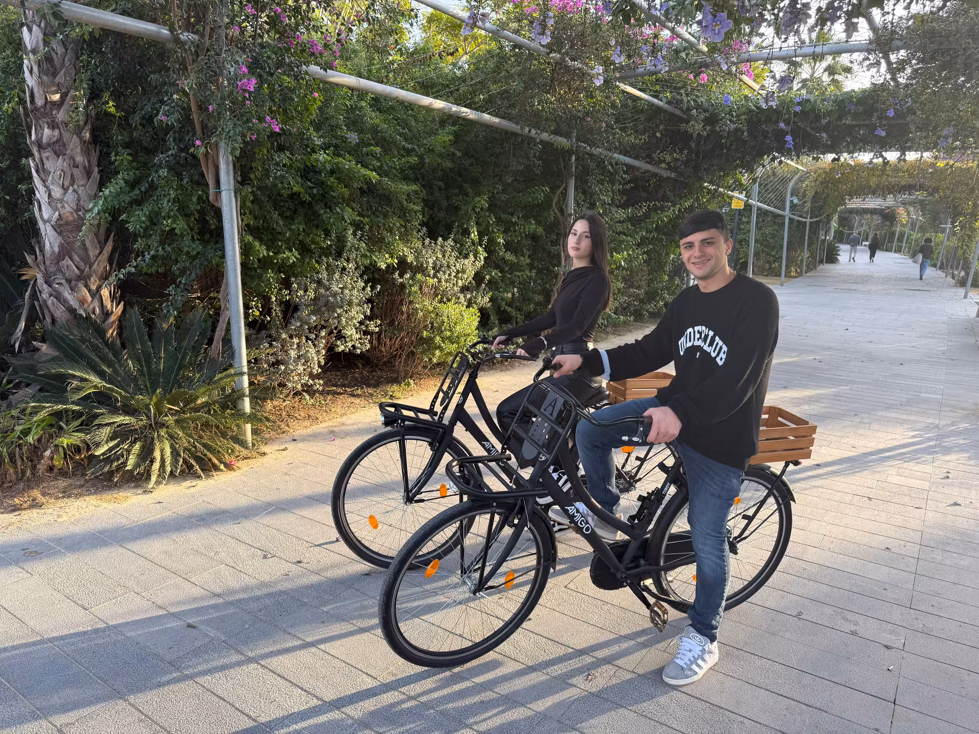 Couple riding Dutch-style Omafiets city bikes on a leafy promenade, ideal for easy city bike rental from €10