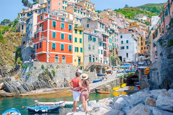 Couple admiring the picturesque waterfront and colorful buildings of Riomaggiore in Cinque Terre.