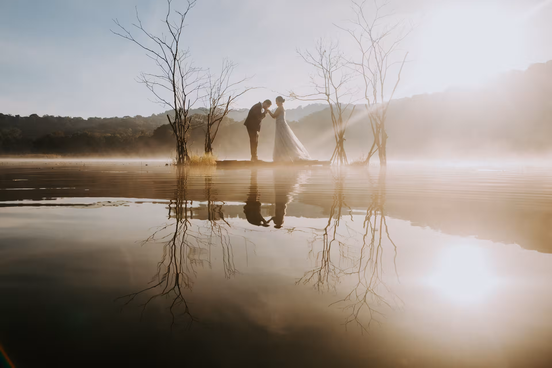 Couple posing romantically on a misty Bali lake with serene reflections during a private photoshoot at sunrise.