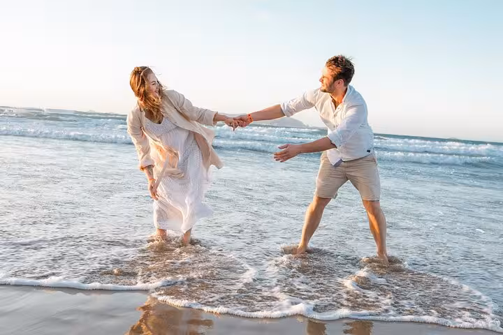 Joyful couple playfully interacts in the waves during a romantic Heraklion beach photoshoot, embracing happiness.