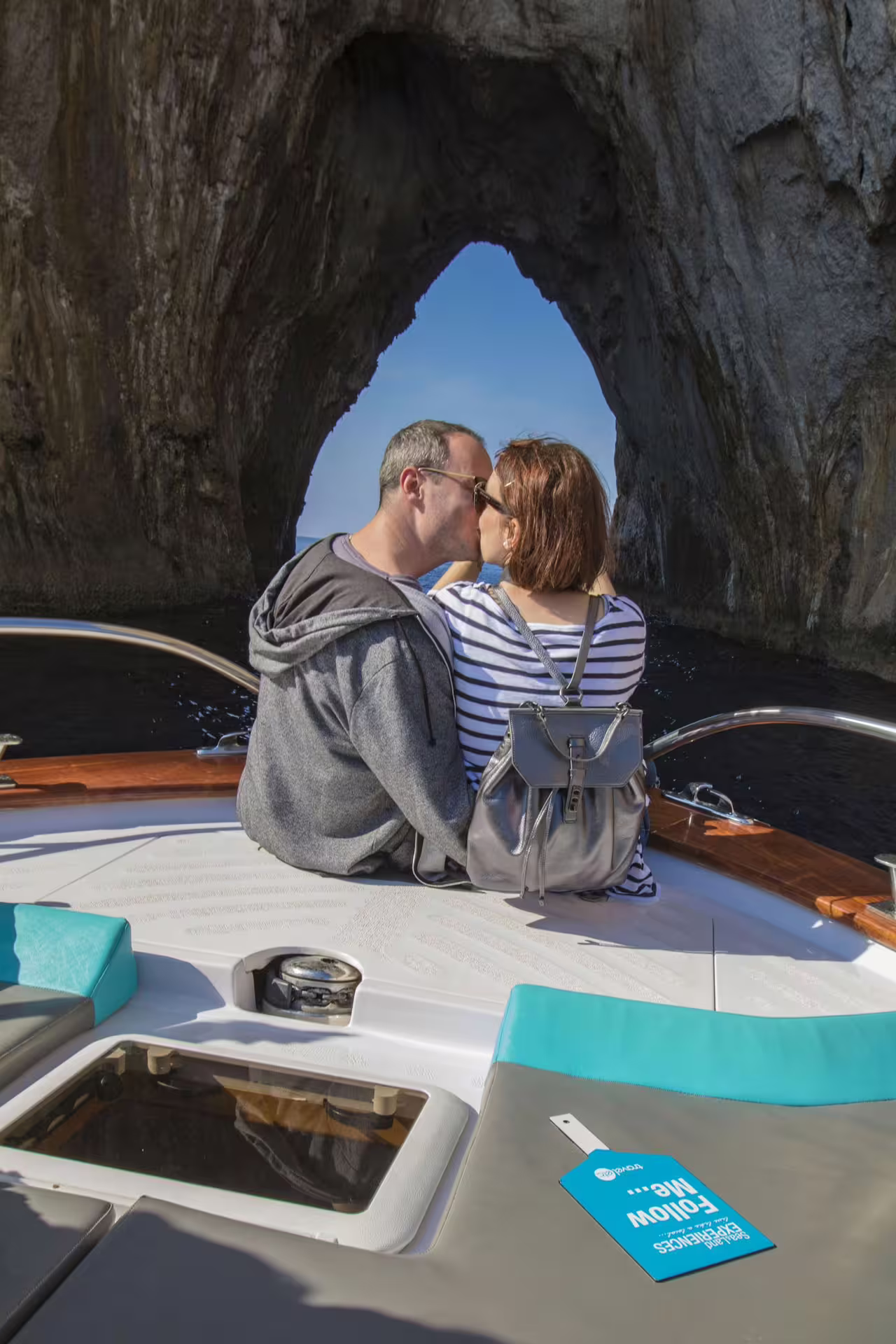 Couple enjoying a romantic moment on a boat tour through the iconic rock formations of Capri Island.