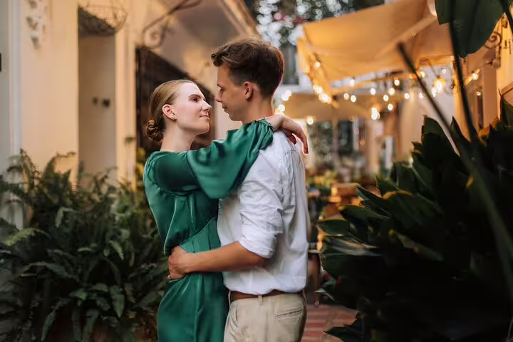 Couple embracing during a romantic evening photoshoot in Marbella, surrounded by warm lights and greenery.