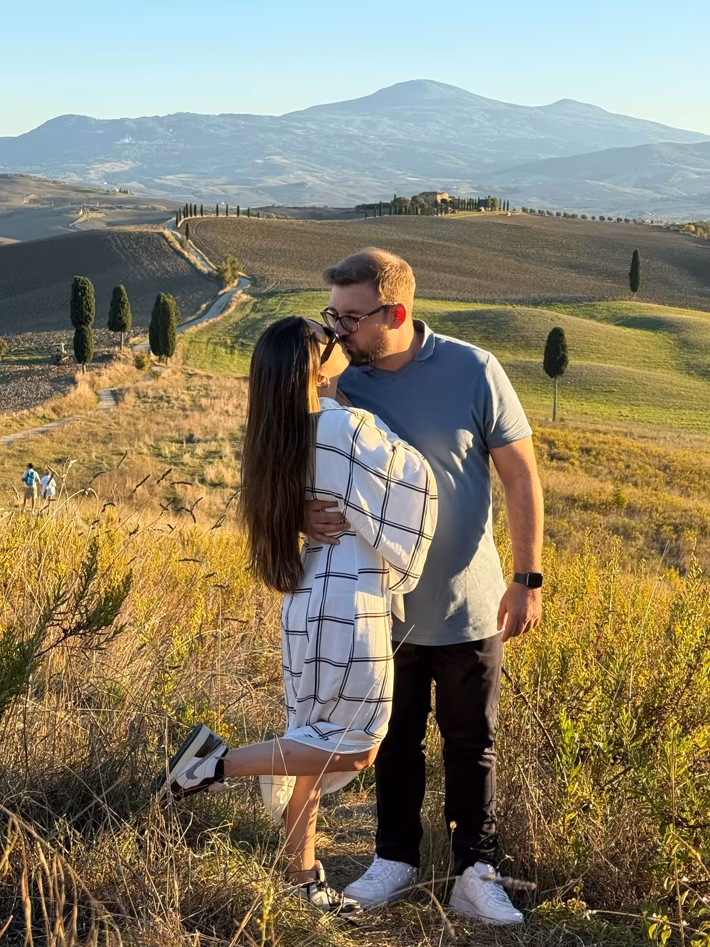 A couple kisses in the picturesque Tuscan countryside near Montepulciano during a romantic day trip.