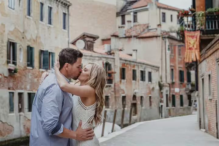Couple shares a romantic kiss on a picturesque Venice street during a private walking tour photo shoot.