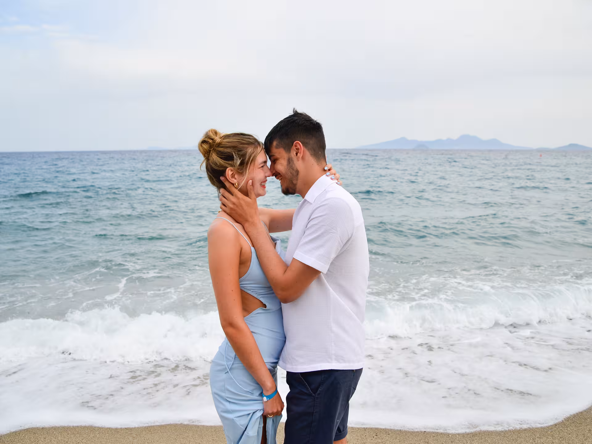 Couple embracing on a sandy beach with waves at Heraklion Venetian Port, perfect for a romantic photoshoot experience.