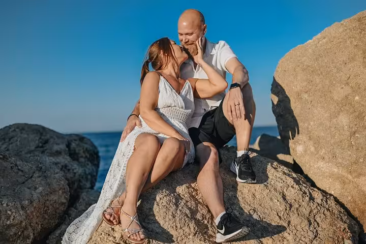 Couple enjoying a romantic moment on rocky coastline during private photoshoot in Hersonissos.