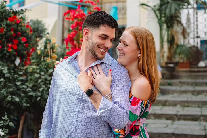 Smiling couple embracing amidst vibrant flowers on a romantic photoshoot in Naples.