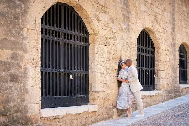 Couple posing romantically by medieval stone arches during a professional photoshoot in Rhodes.