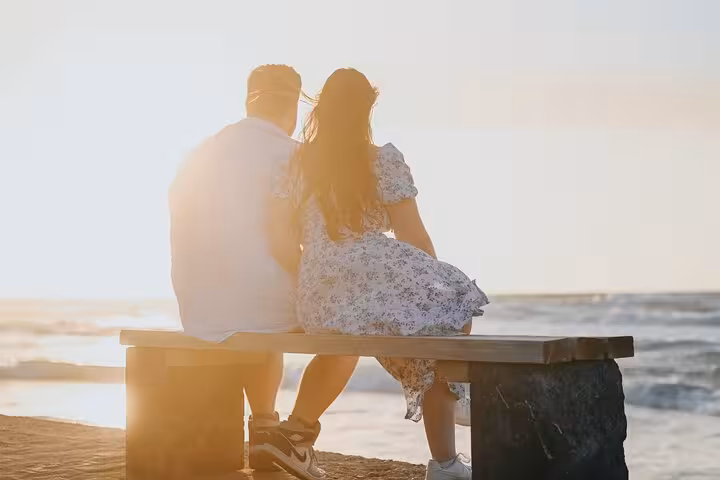 Couple enjoying a romantic sunset on a beach bench during a private photoshoot in Gouves, capturing serene ocean views.