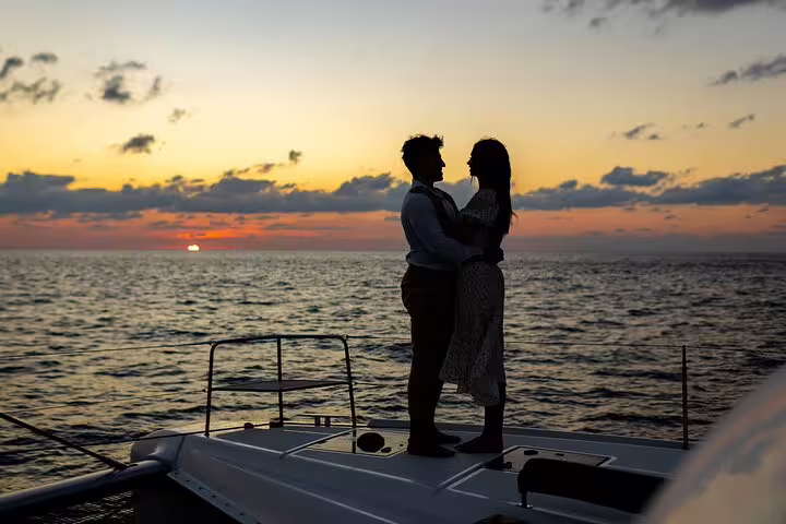 Couple enjoying a romantic sunset on a catamaran cruise in Santorini, with a breathtaking ocean view.