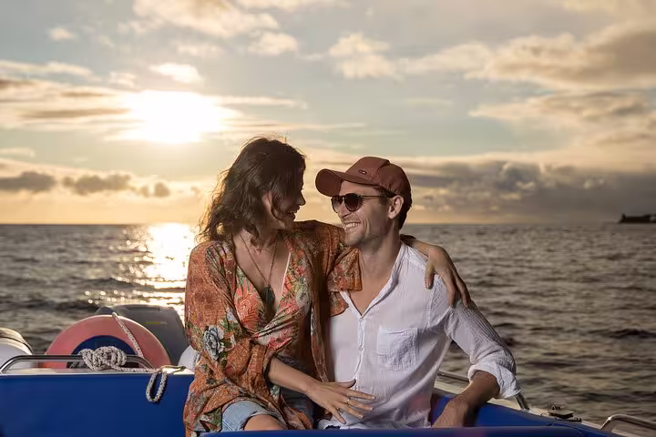 Couple enjoying a romantic sunset moment on a private cruise, surrounded by sparkling ocean waters and golden skies.