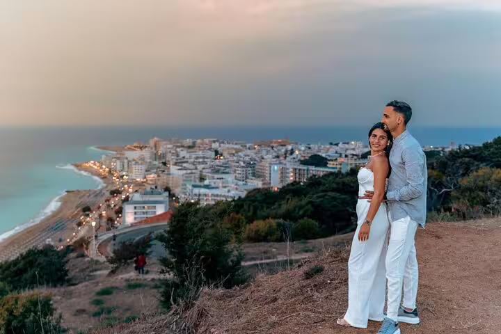 Couple enjoying a romantic sunset view over Rhodes cityscape during a private photoshoot experience.