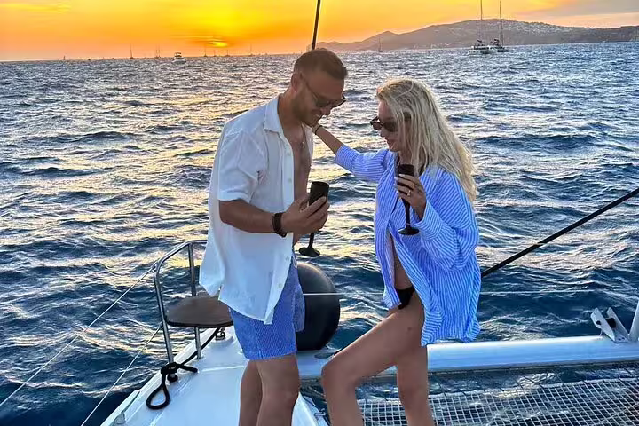 Couple savoring a romantic sunset over the Aegean Sea during a Santorini private catamaran cruise.