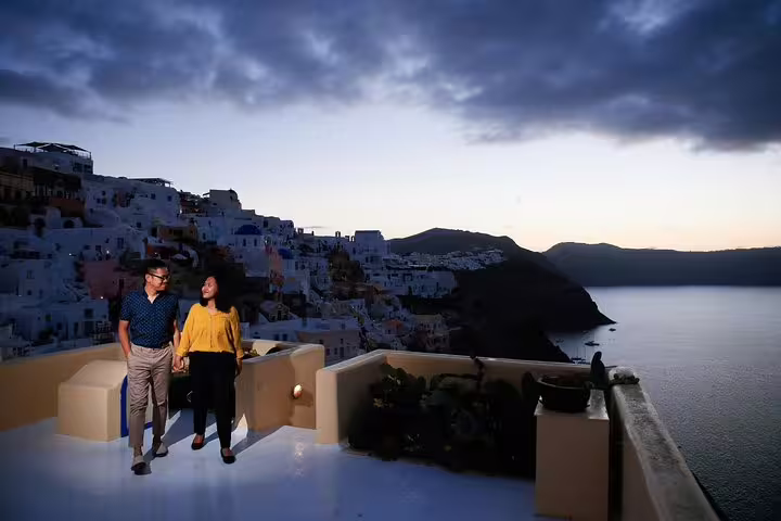 Couple enjoying a romantic sunset view over Santorini's iconic white-washed buildings during a photography tour.