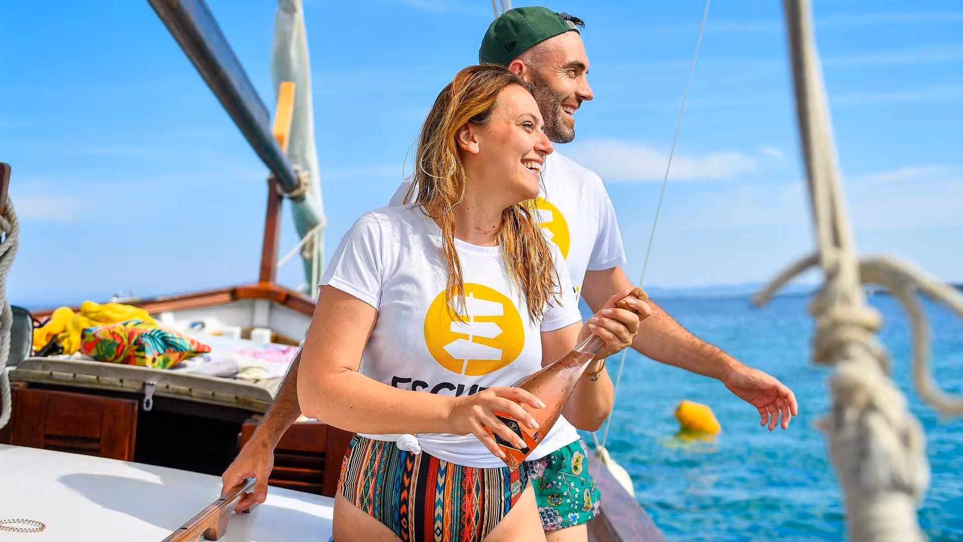 Couple celebrating on a sailboat with a bottle of wine during a scenic Asinara sailing trip from Stintino.