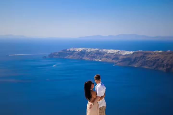 Couple embracing on a Santorini cliffside with breathtaking views of the Aegean Sea, captured during a photography tour.