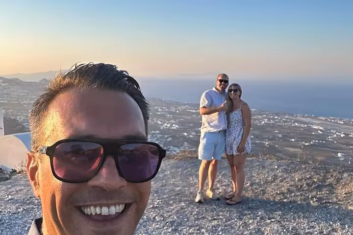 Couple viewpoint selfie above Santorini coastline at sunset, highlight of one-day cruise ship island tour