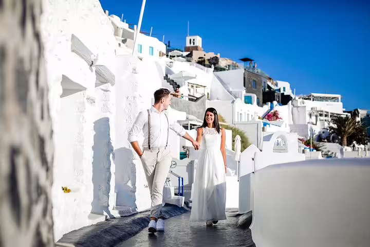 Couple walking hand in hand through the picturesque white streets of Santorini during a personal vacation photography tour.