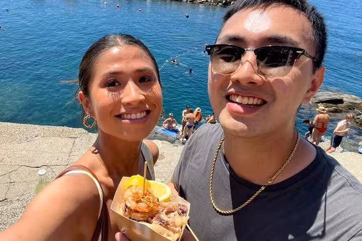 Couple savoring seafood with picturesque sea backdrop during Pisa and Cinque Terre day trip from Florence.