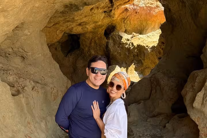 Couple posing inside a seaside cave stop on a 3 beaches in 1 day tour, coastal adventure experience