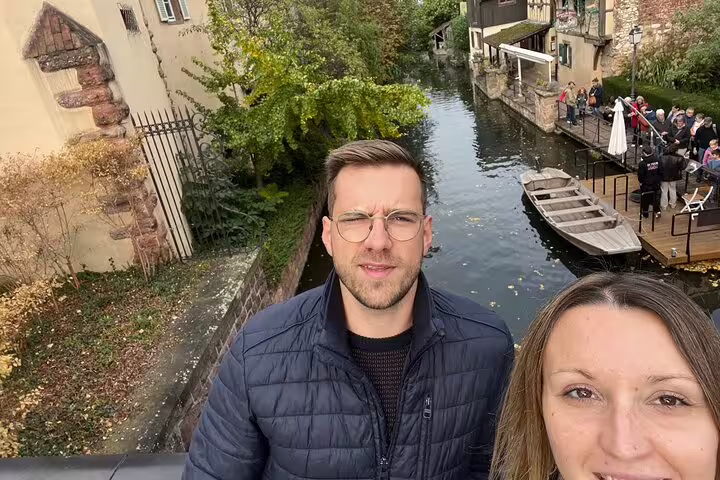 Couple selfie by Colmar’s Little Venice canal, perfect stop on a self-guided scavenger hunt walking tour