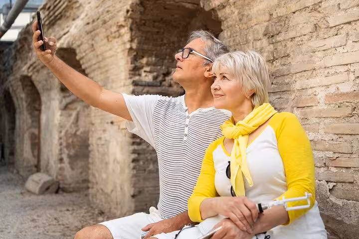 Couple taking a selfie against ancient stone walls during a private 2-hour city walk in Lourdes with local guide.