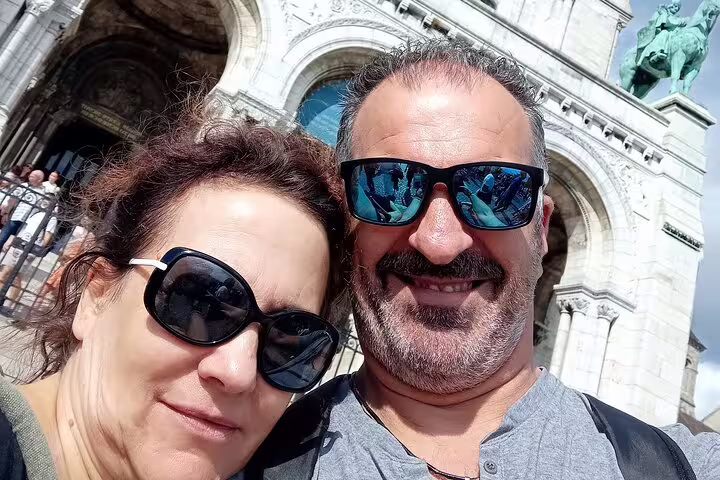 Couple selfie by Sacré-Cœur Basilica arches in Montmartre on a Paris scavenger hunt self-guided tour