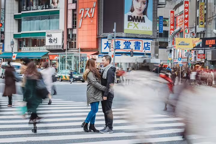 Couple posing at Shibuya Crossing with Tokyo personal travel photographer, motion-blur crowds and neon signs