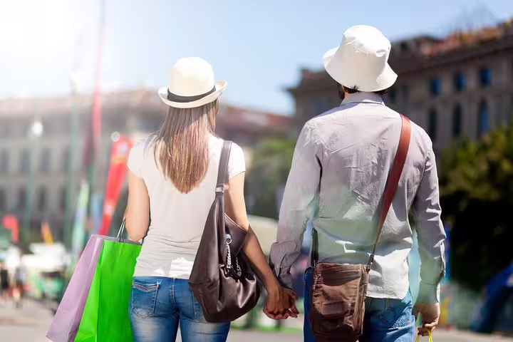Couple holding hands with colorful bags on a Rome shopping tour, enjoying a VIP half-day experience with personal shopper