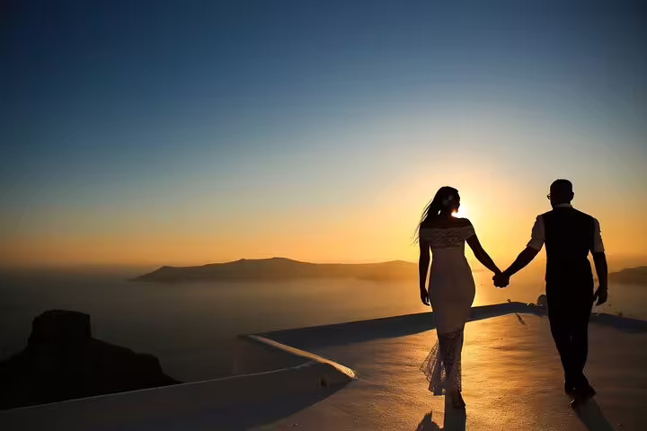 Silhouette couple holding hands at Santorini sunset caldera, romantic proposal photographer capturing the moment