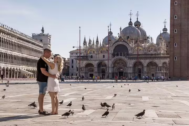 Couple embraces in St. Mark's Square, Venice, surrounded by pigeons on an early morning photo tour in Italy.