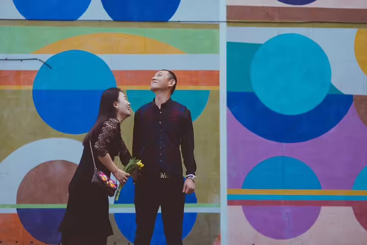 Joyful couple posing against colorful street art in Dublin, capturing moments on a private photography tour.