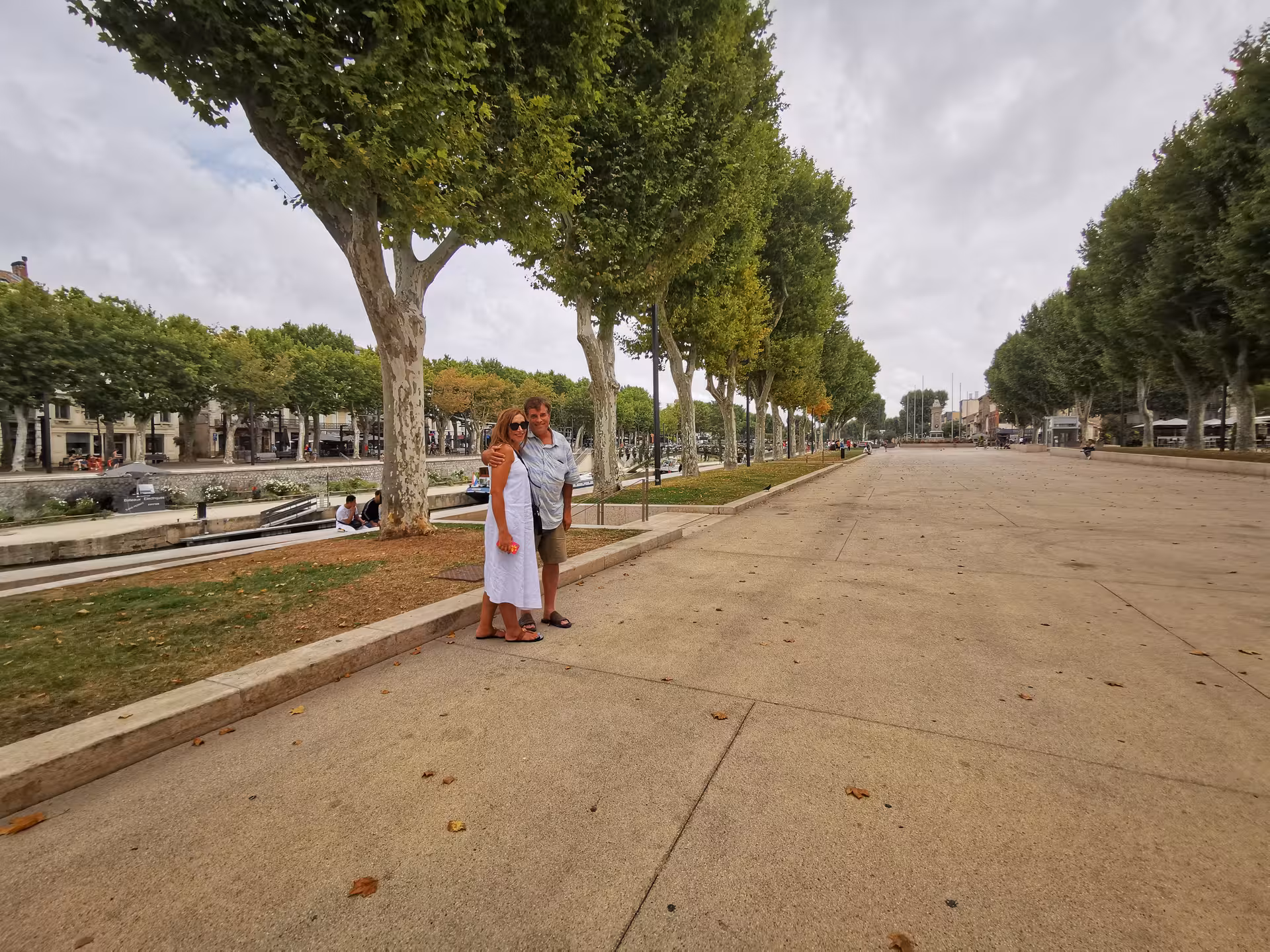 Couple strolling along Narbonne’s Canal de la Robine promenade on a private shore excursion from Sète