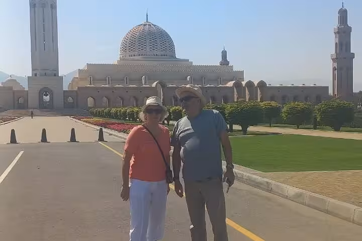 Couple posing outside Sultan Qaboos Grand Mosque in Muscat during a private half-day city and Bimmah Sinkhole tour