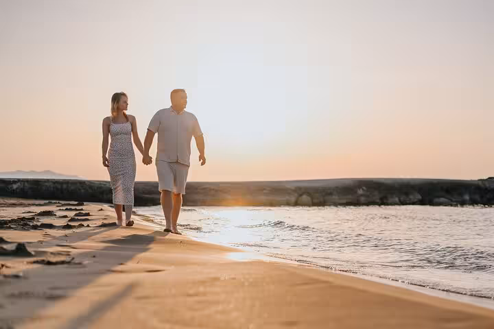 Couple strolling hand in hand along Gouves beach at sunset, ideal setting for a serene private photoshoot.