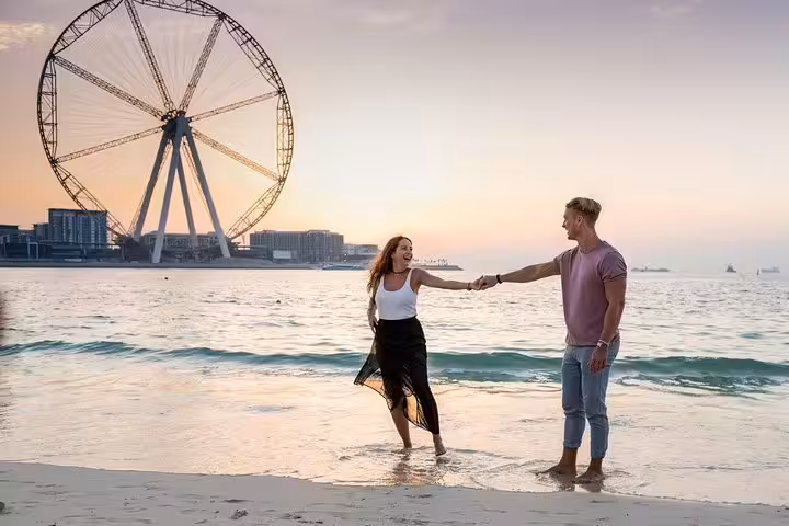 Couple beach photo session at sunset with Ain Dubai backdrop on a private travel photographer tour in Dubai Marina